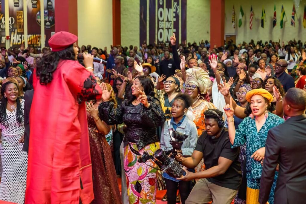 Nigerian Gospel artist performing live on a brightly lit stage to a large, enthusiastic audience, symbolizing the genre's powerful rise and mainstream appeal.